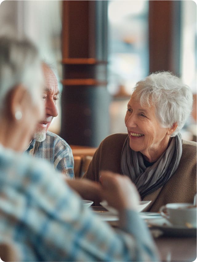 Three senior citizens delight in a communal meal within a senior living dining room, showcasing the vibrant community atmosphere fostered by Cura Connect. This scene highlights Cura Connect’s dedication to enhancing senior living communities by optimizing purchasing, food production, and menu development through its membership services network.